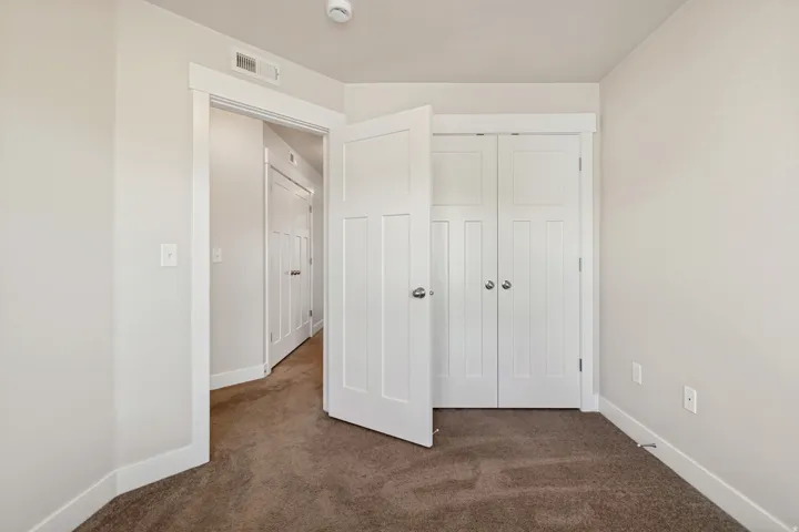 Neutral wall paint, plush carpet flooring, white trim, and white paneled doors