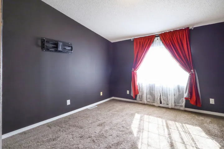Carpeted flooring, white trim, and a window with a white curtain rod