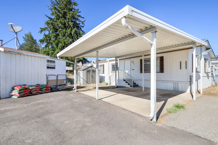 Carport with concrete pad, exterior storage shed, and additional outdoor shed