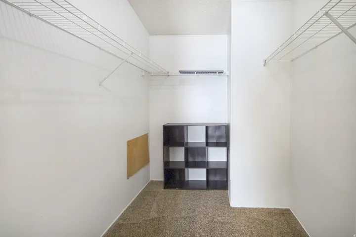 Carpet flooring, white walls, and wire shelving