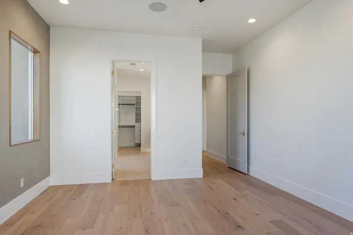 Primary Ensuite Bedroom has light-toned wood flooring, recessed ceiling lighting, three large windows, black ceiling fan, and a textured accent wall