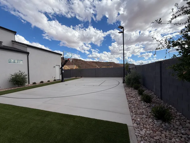 Expansive backyard featuring artificial turf, a built-in trampoline, sport court and full landscaping