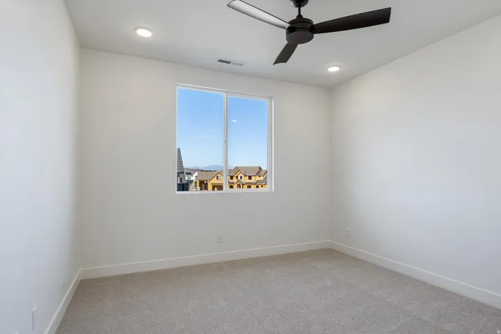 This bedroom has recessed ceiling lighting, light paneled doors with brass hardware, plush carpeting, and light walls