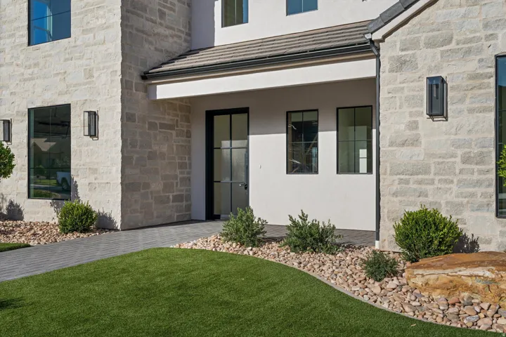 Stone facade with stucco accents, black frame windows, dark tile roof, and a covered entry