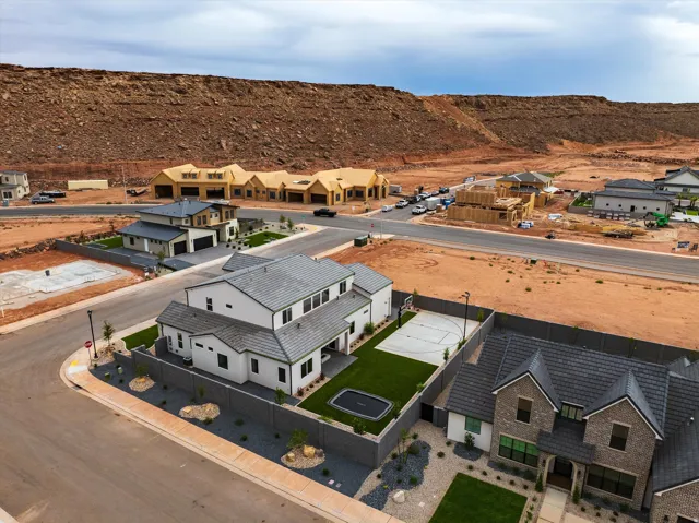 Contemporary residence featuring a paved driveway, a basketball court, a trampoline, and a surrounding privacy fence