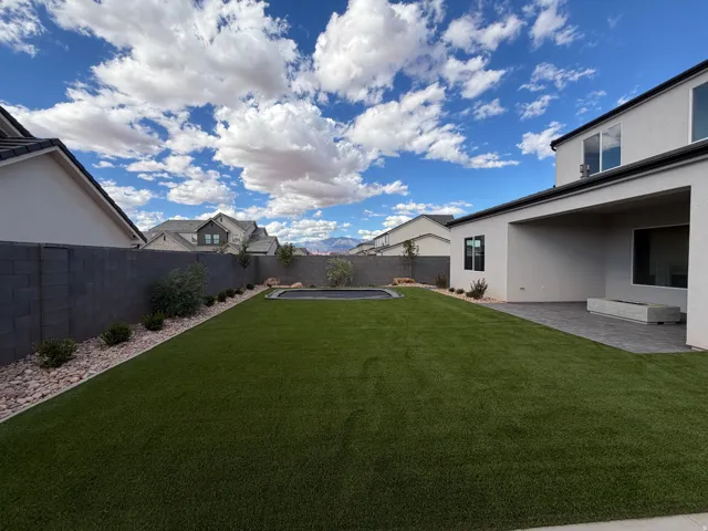 Expansive backyard featuring artificial turf, a built-in trampoline, sport court and full landscaping