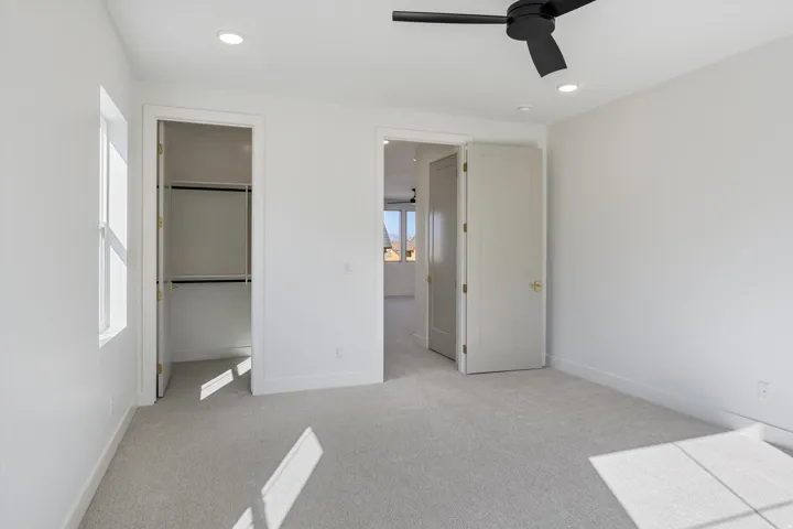 This bedroom has plush carpeting, recessed lighting, two windows and a modern ceiling fan