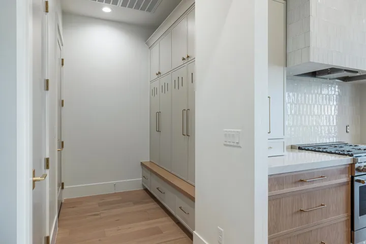 Built-in cabinetry with brass hardware, wood flooring, and recessed lighting