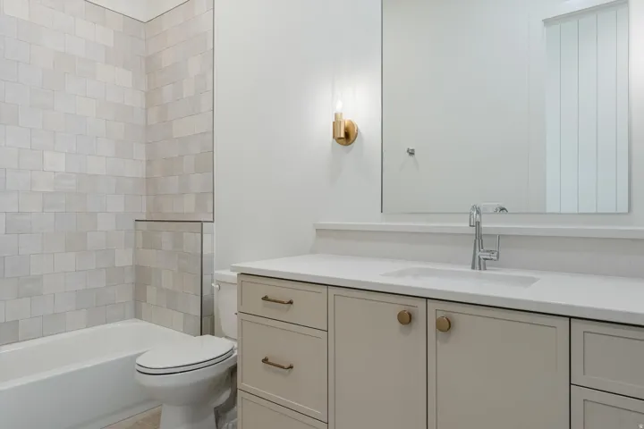 Bathtub and shower combination with light-toned tiled surround
