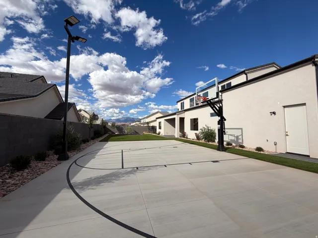 Expansive backyard featuring artificial turf, a built-in trampoline, sport court and full landscaping