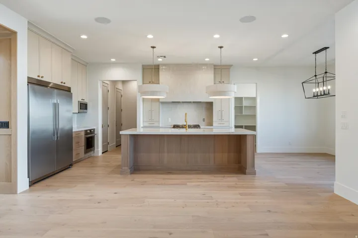 Expansive kitchen with wood-finish flooring, a large central island, stainless steel appliances, and recessed lighting
