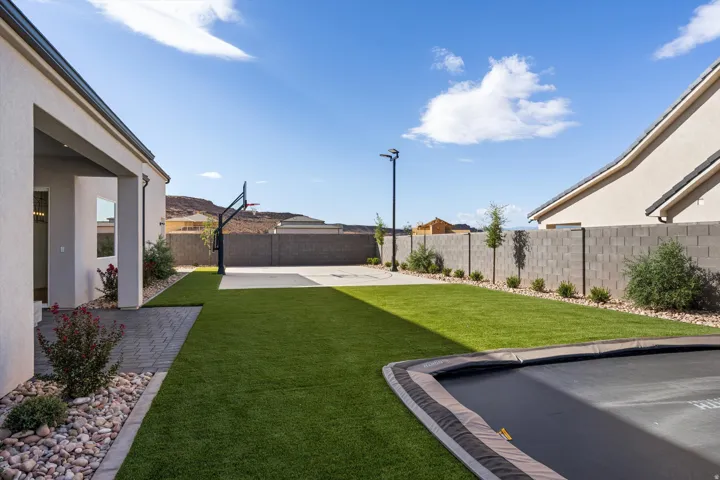 Expansive backyard featuring artificial turf, a built-in trampoline, sport court and full landscaping
