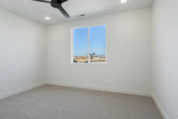 This bedroom has recessed ceiling lighting, ceiling fan, neutral carpeting, paneled interior doors, and a closet with built-in shelving