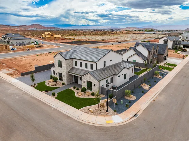 Stone and stucco exterior with multiple gables, a gray tile roof, and a dark gray driveway