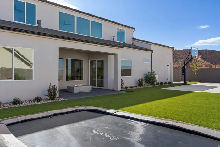 Expansive backyard featuring artificial turf, a built-in trampoline, sport court and full landscaping