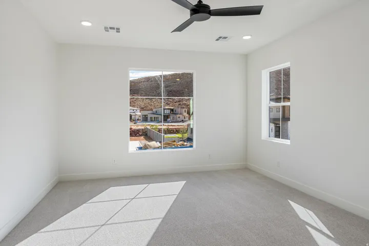 This bedroom has plush carpeting, recessed lighting, two windows and a modern ceiling fan
