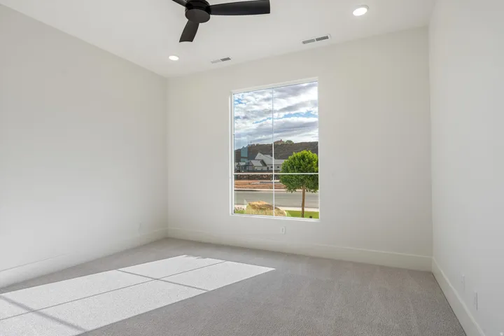 Large window, recessed lighting, ceiling fan, and light colored wall-to-wall carpeting