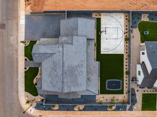Manicured landscaping, paved driveway, asphalt shingle roof, paved basketball court, turf lawn
