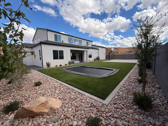 Expansive backyard featuring artificial turf, a built-in trampoline, sport court and full landscaping