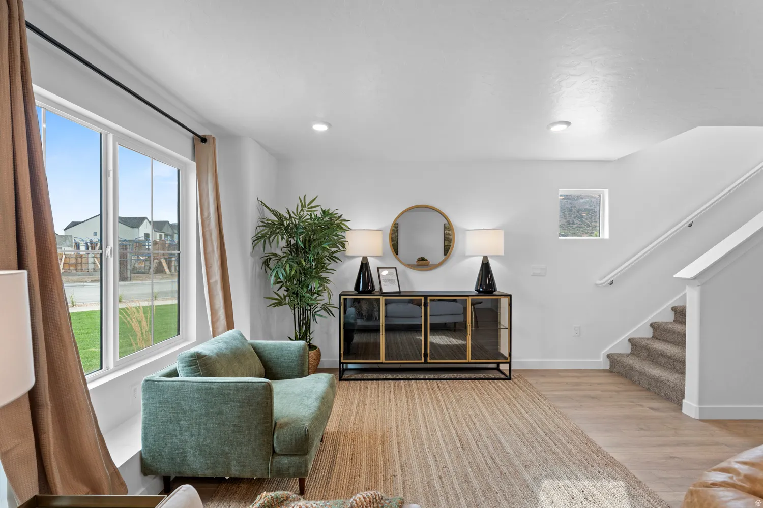 Expansive windows, recessed lighting, wood-finish flooring, a contemporary staircase with carpeted treads, and a built-in console cabinet