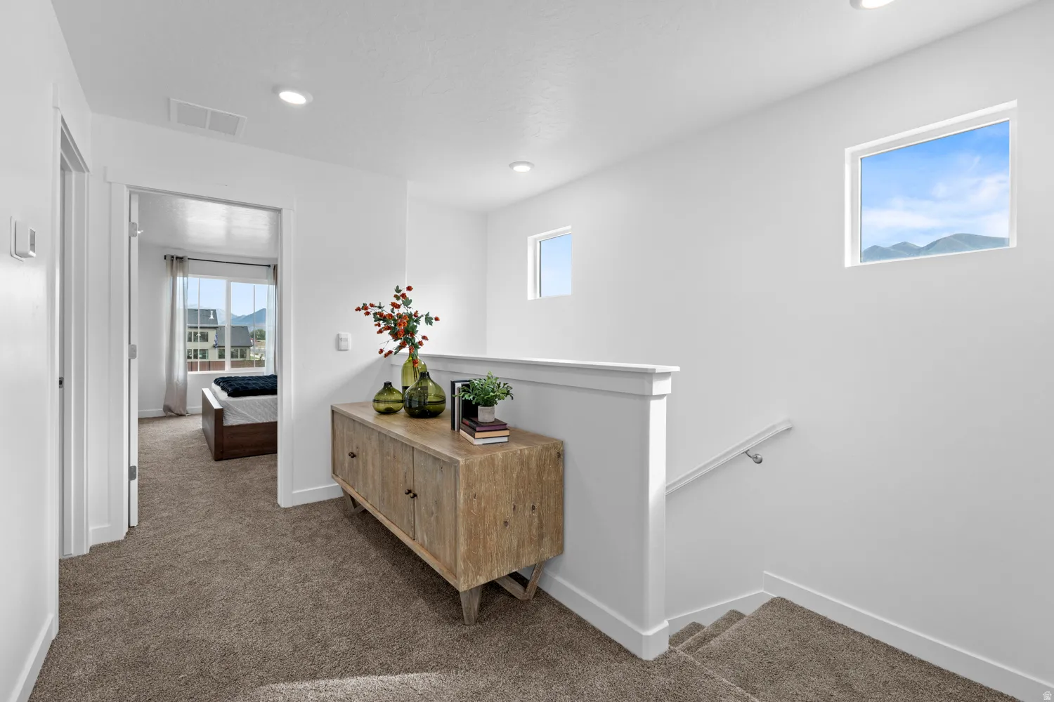 Carpeted hallway with recessed lighting and square transom windows
