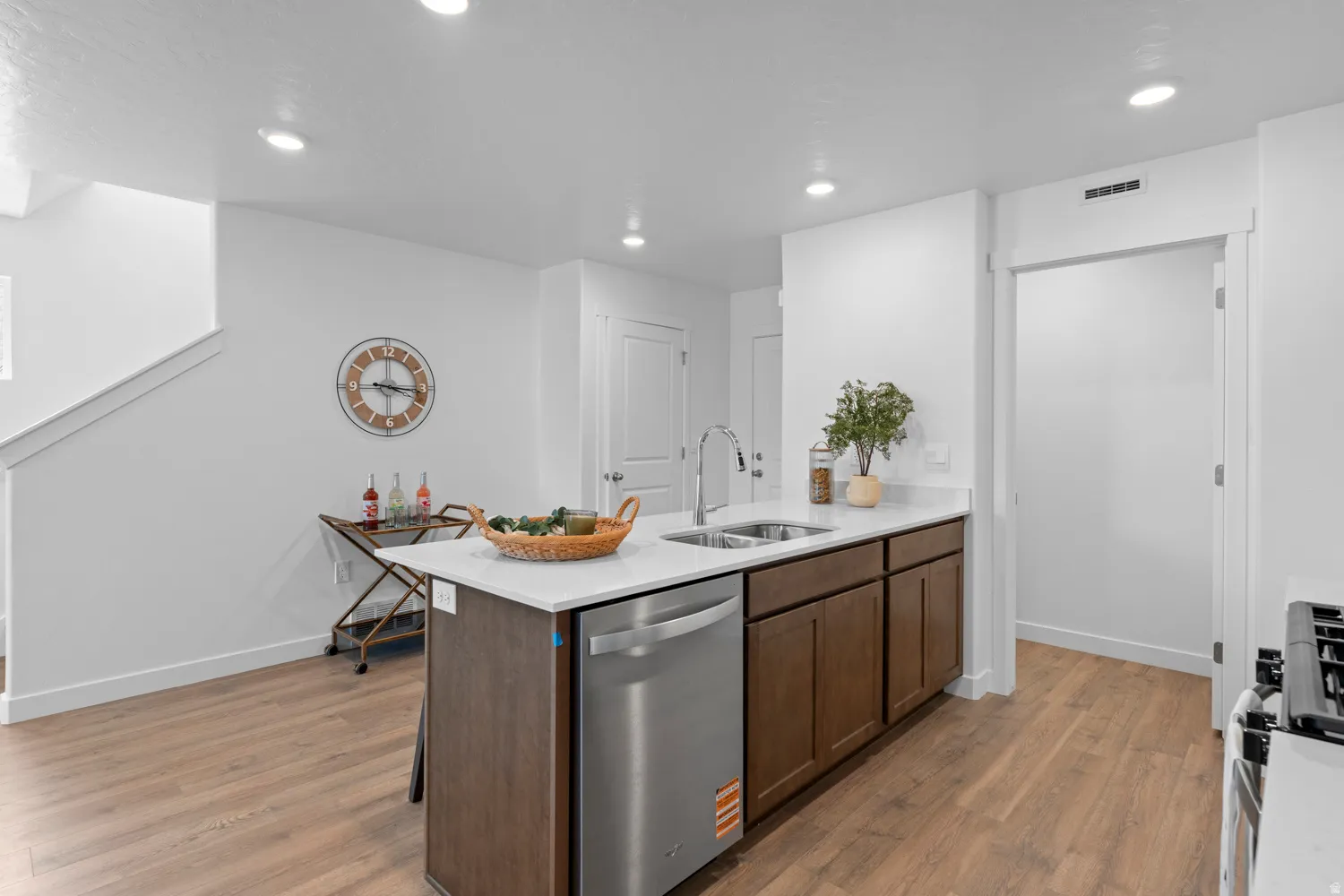 Kitchen island with a stainless steel dishwasher, dual basin sink, and a high-arc faucet
