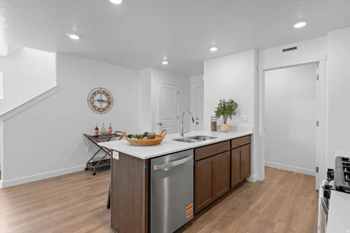 Kitchen island with a stainless steel dishwasher, dual basin sink, and a high-arc faucet