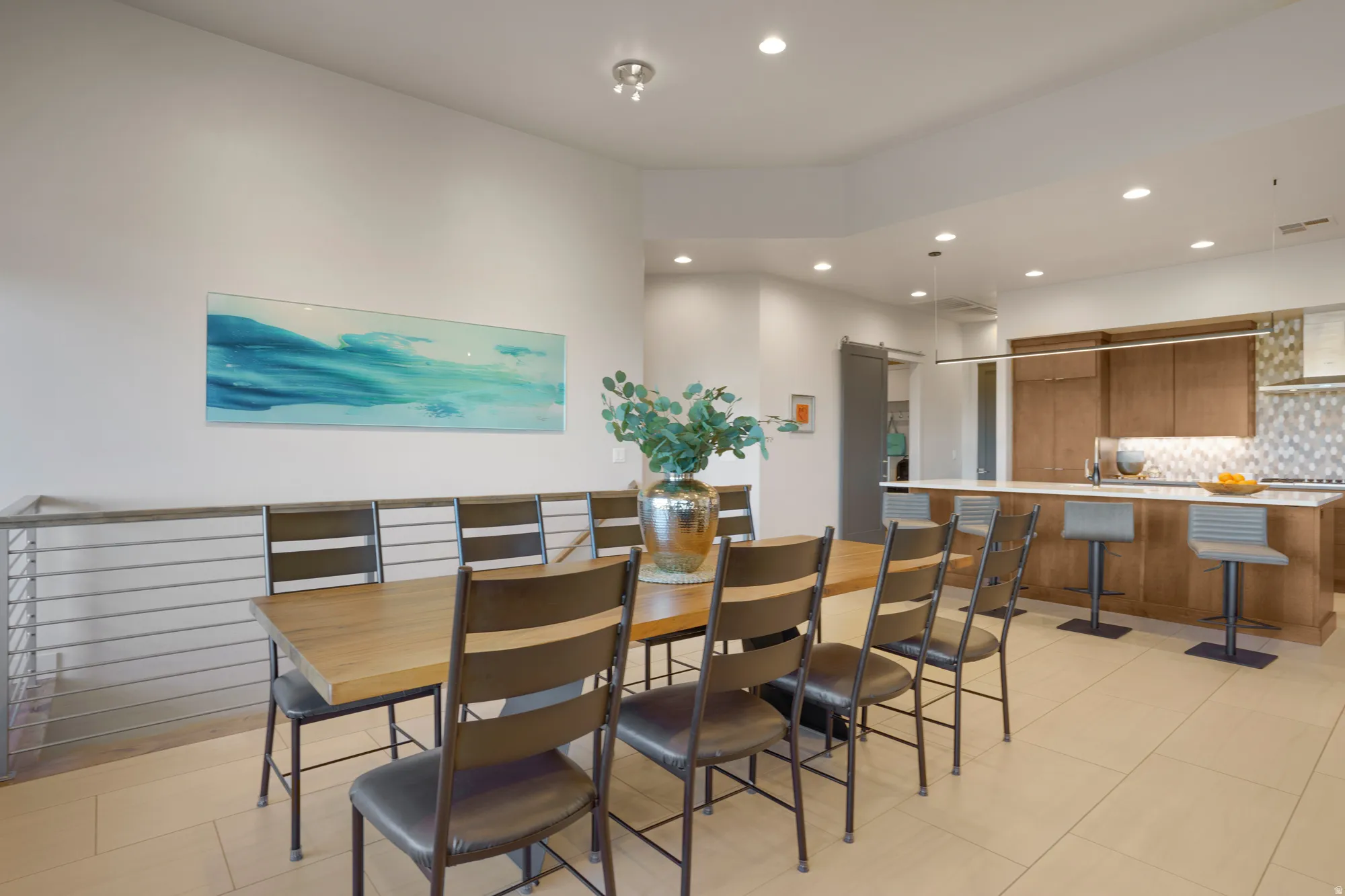 Recessed lighting, wood-finish flooring, stainless steel railing, wood-finish cabinetry, and a tile backsplash