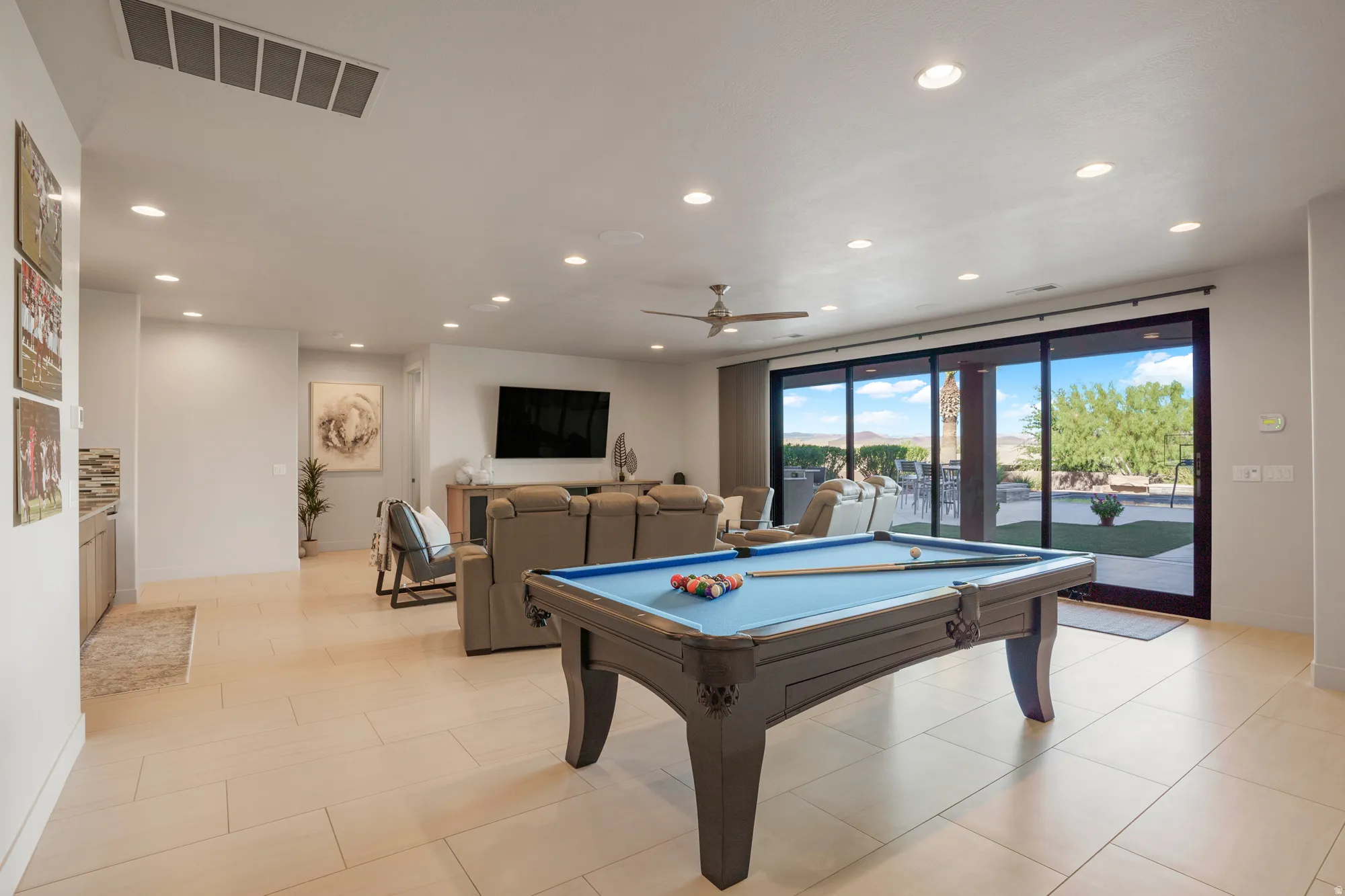 Expansive open-concept living area featuring light-toned flooring, recessed lighting, and a ceiling fan
