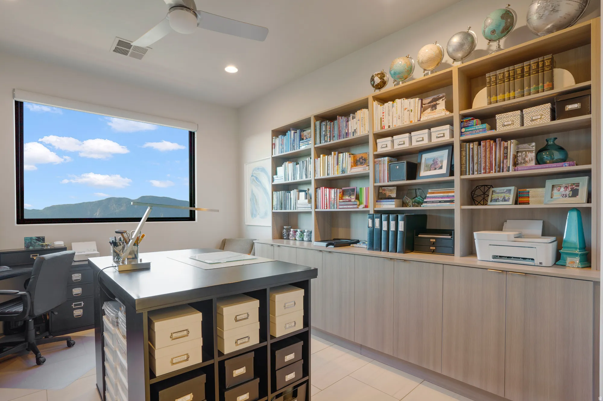 Built-in shelving with integrated cabinetry, recessed lighting, ceiling fan, and a wide window