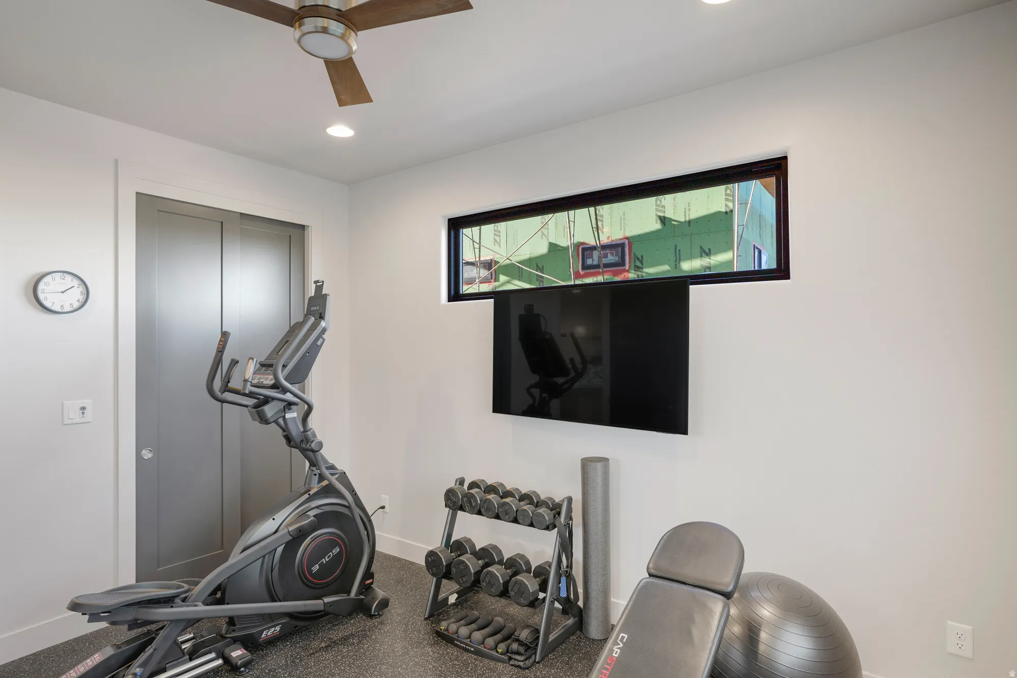 Wall-mounted television, wood-finish ceiling fan, recessed lighting, and horizontal window