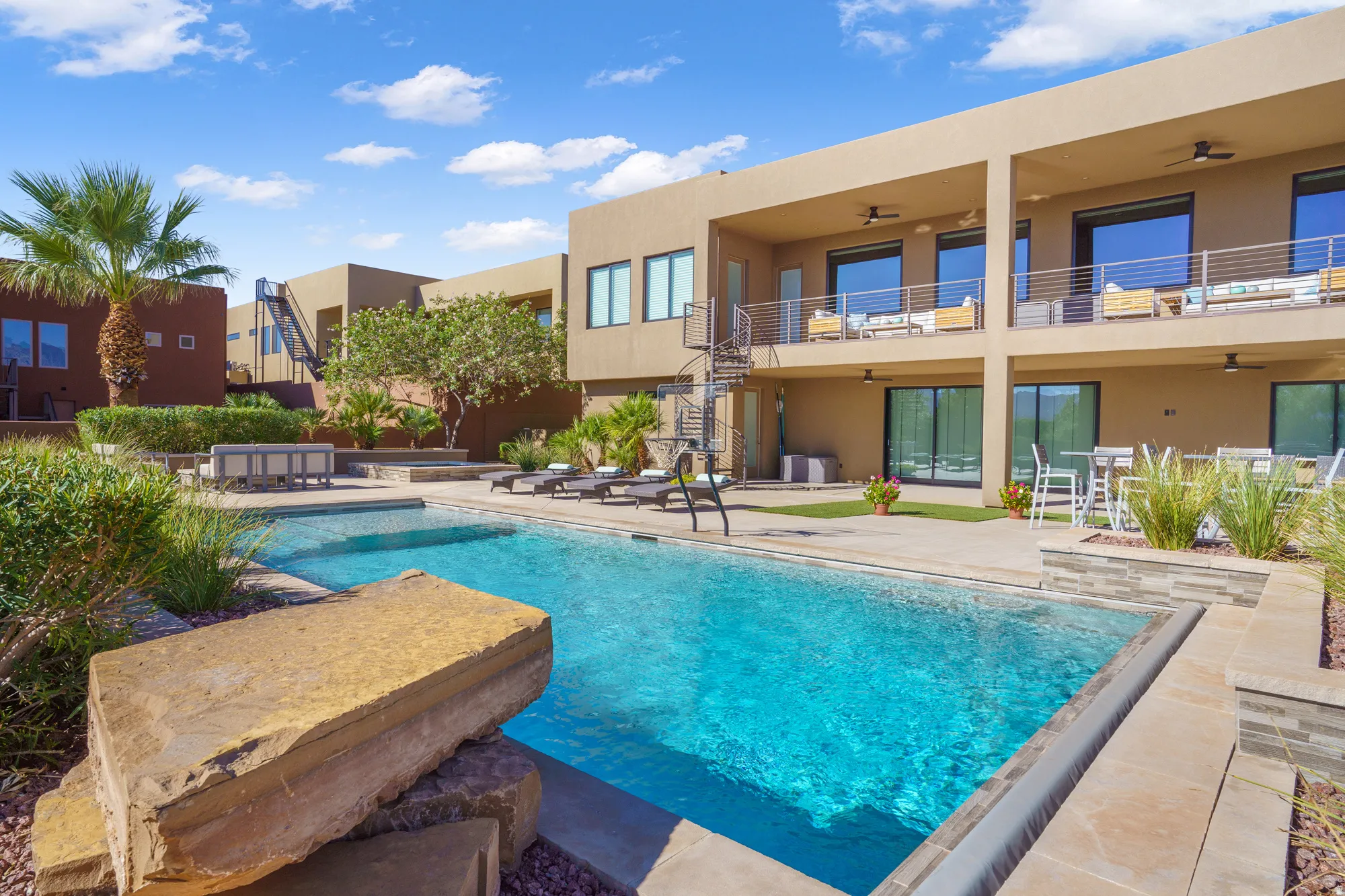 Contemporary architecture featuring a rectangular swimming pool, multiple balconies with metal railings, and a spiral staircase