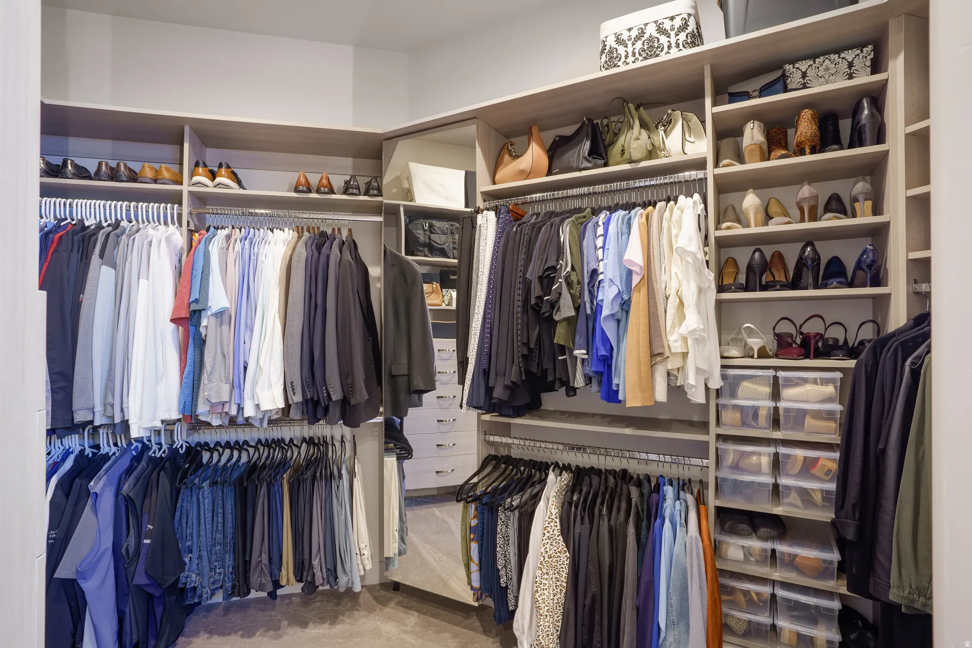 Walk-in closet featuring extensive built-in shelving, multiple hanging rods, and integrated drawers