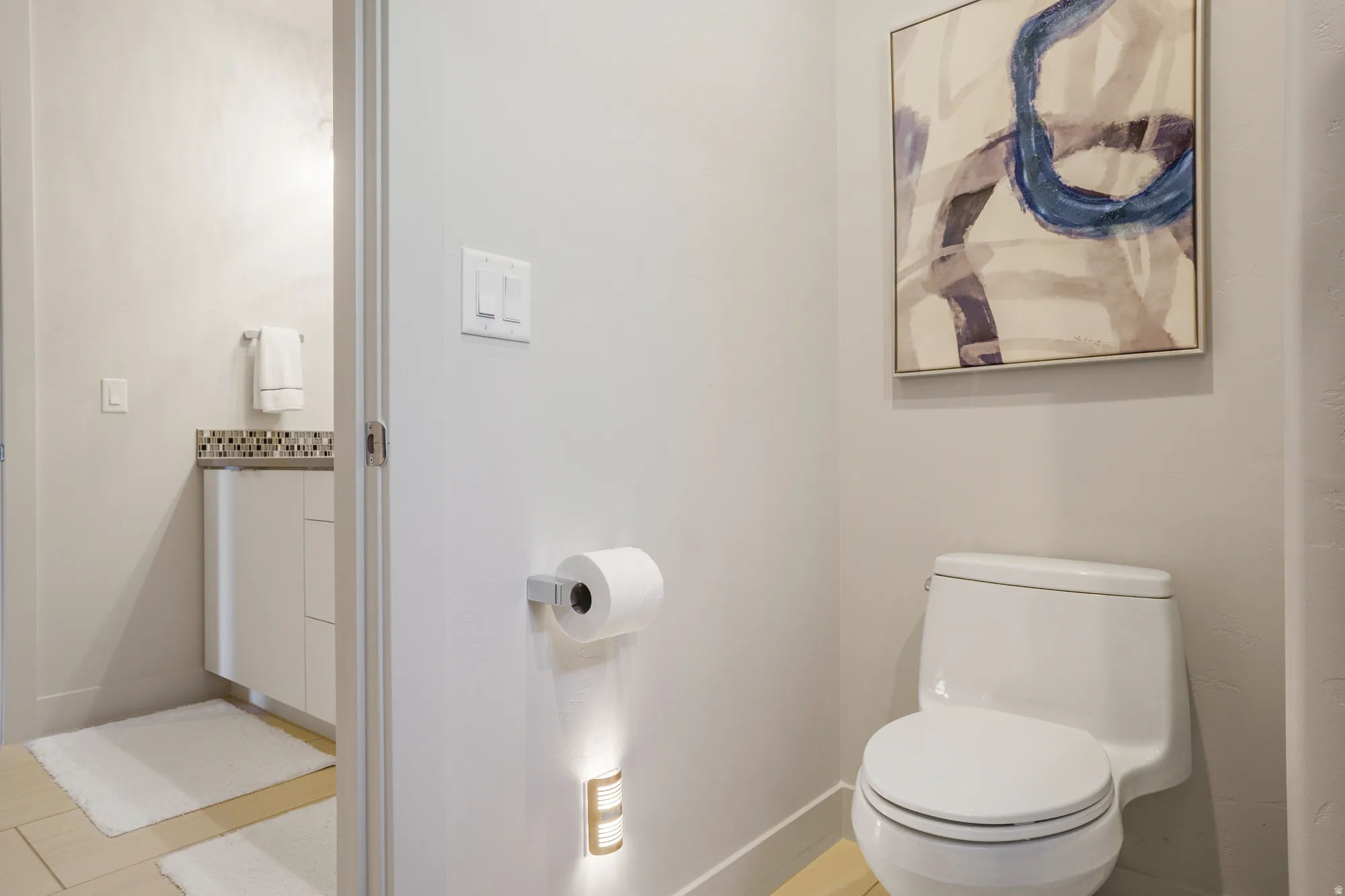 White toilet with wall-mounted light fixture