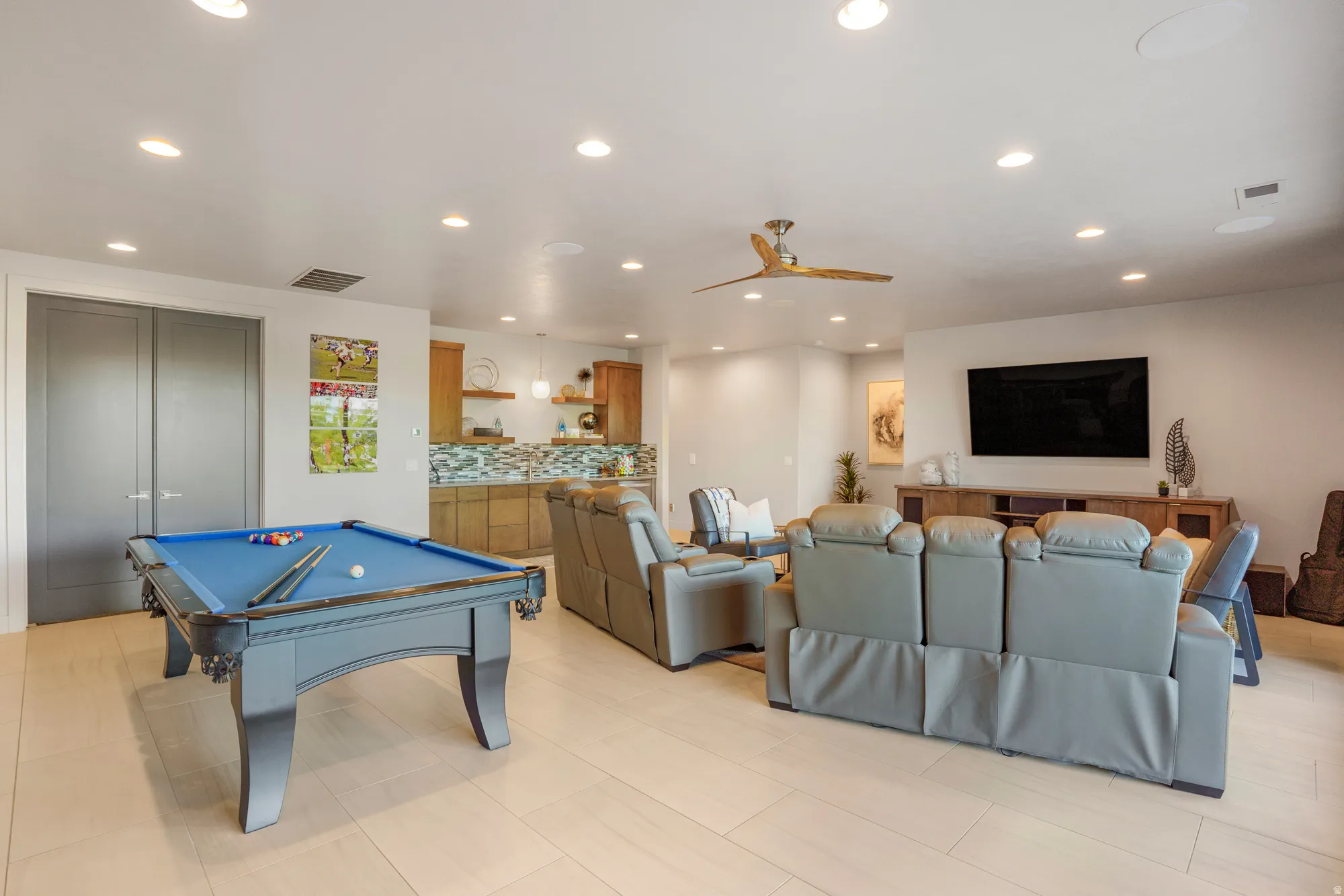 Open-concept living area with light-toned wood-finish flooring, recessed lighting, and a ceiling fan