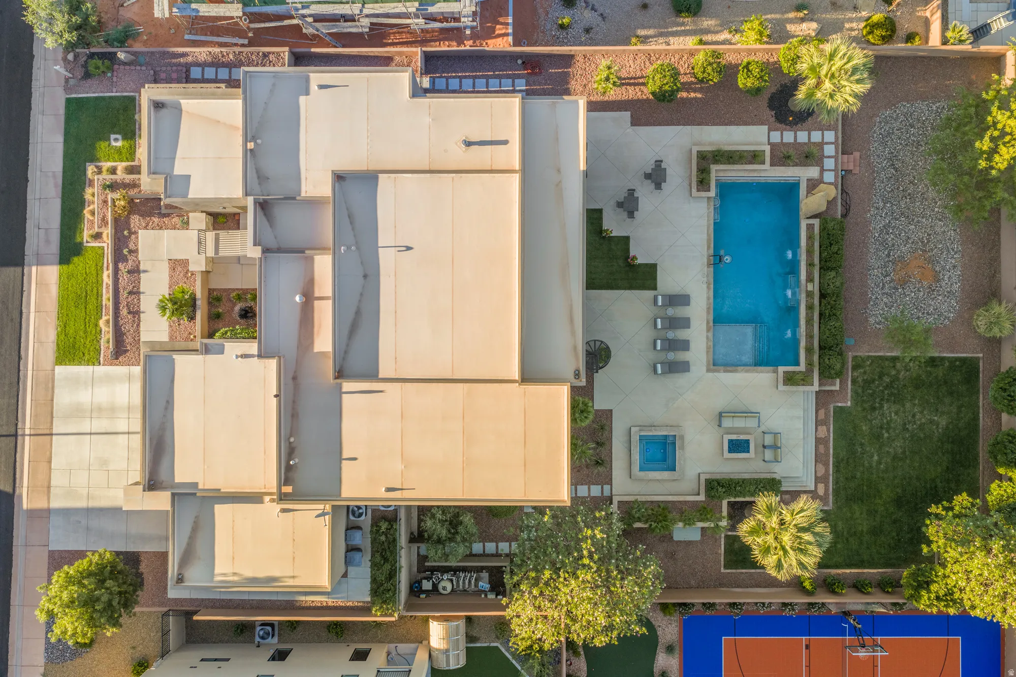 Expansive exterior with a rectangular pool, integrated spa, and an adjacent sports court