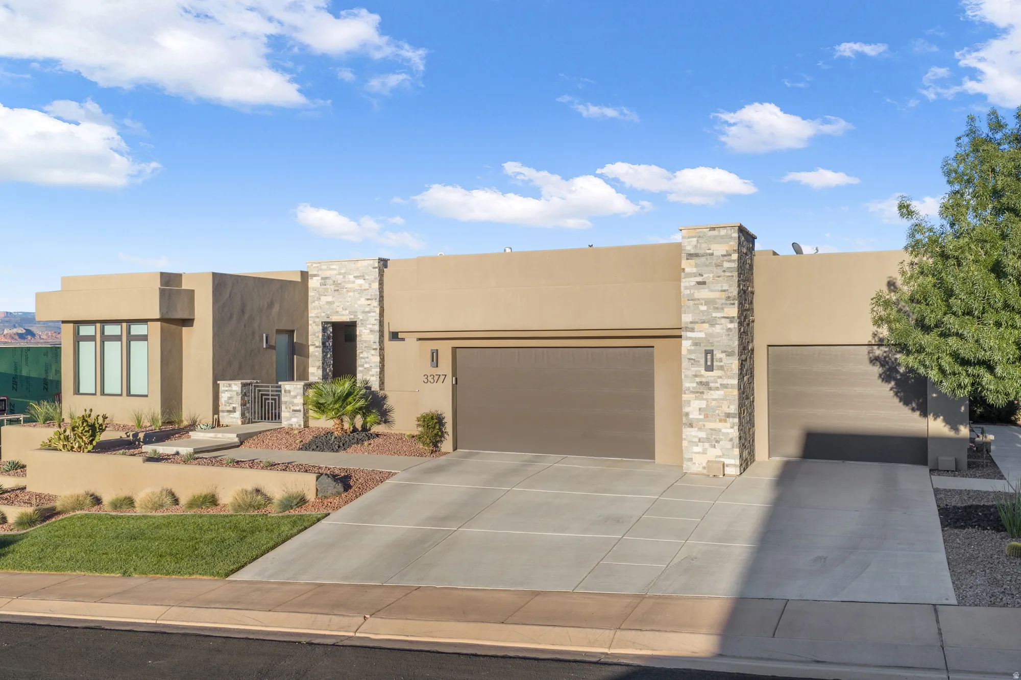 Stucco exterior with stone accents, integrated two-car garage, and desert landscaping