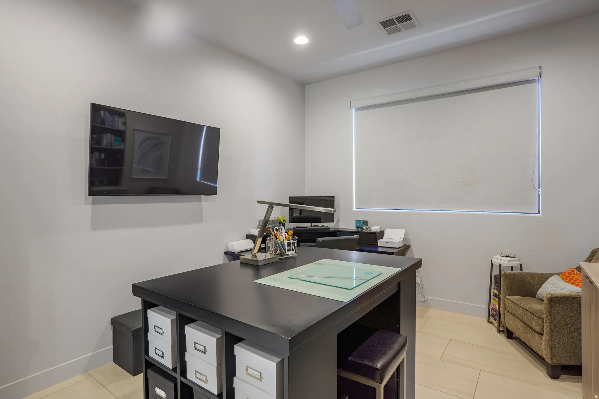 Bright room featuring light-toned tile flooring and a large window with a roller shade