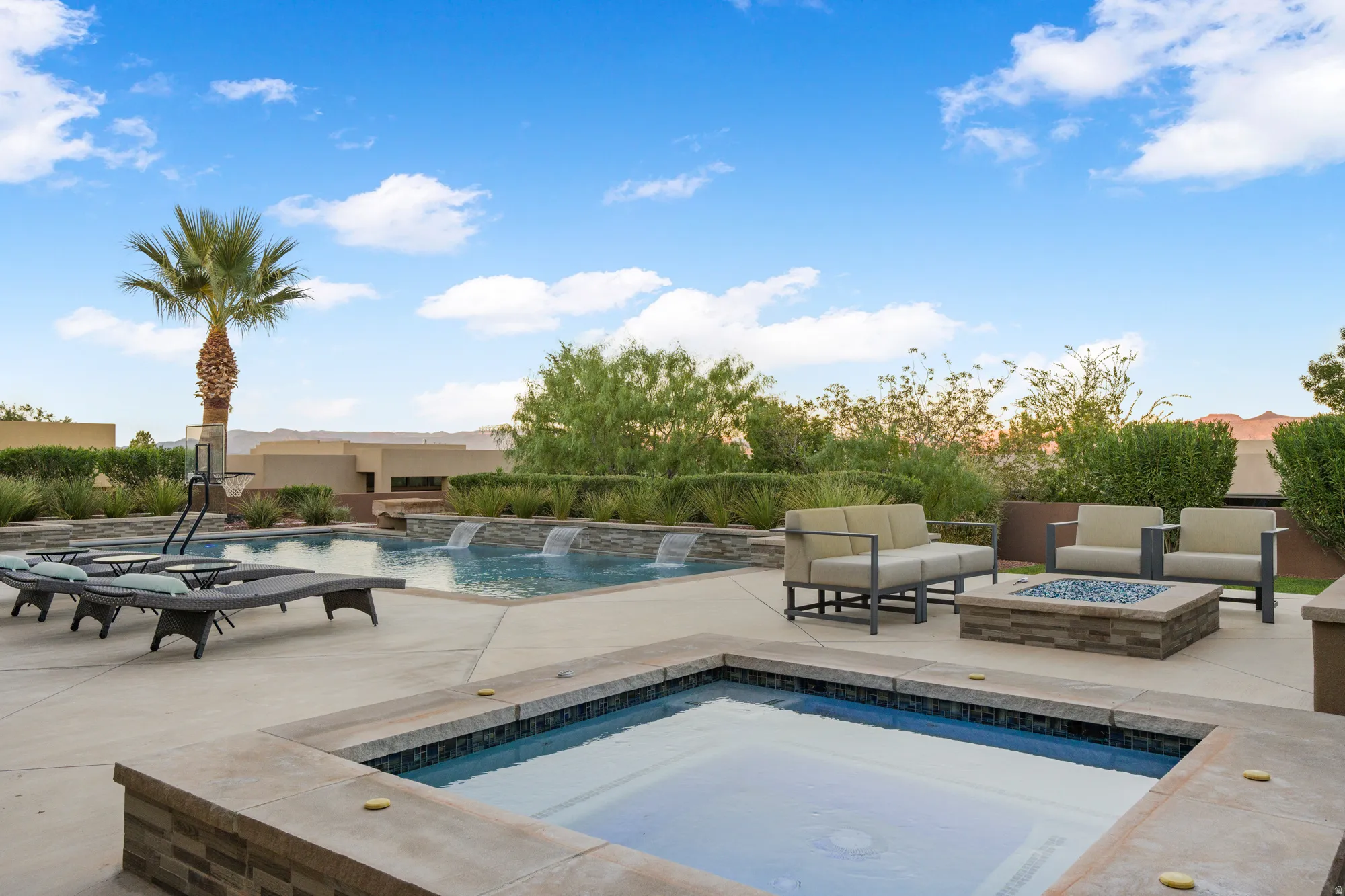 Resort-style backyard featuring a pool with water features, an integrated spa, and a built-in fire pit