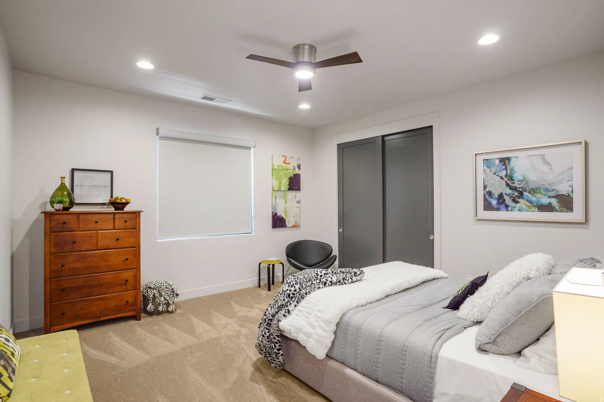 Recessed lighting and a ceiling fan fixture illuminate the space, complemented by a window with roller shade