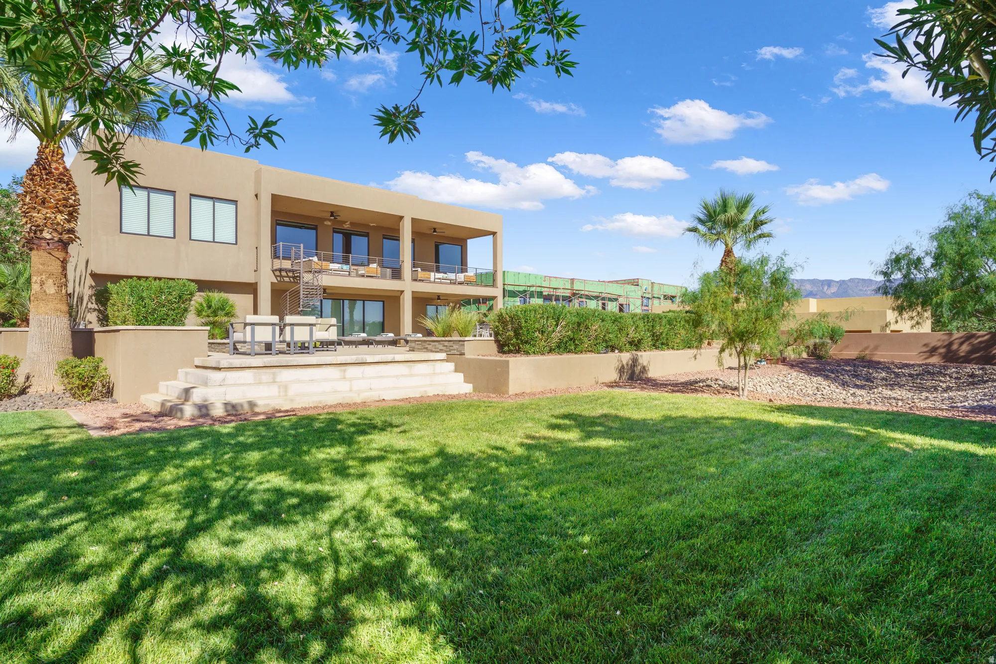 Expansive rear lawn, multi-level terrace, upper-level balcony, lower-level patio, and mature landscaping