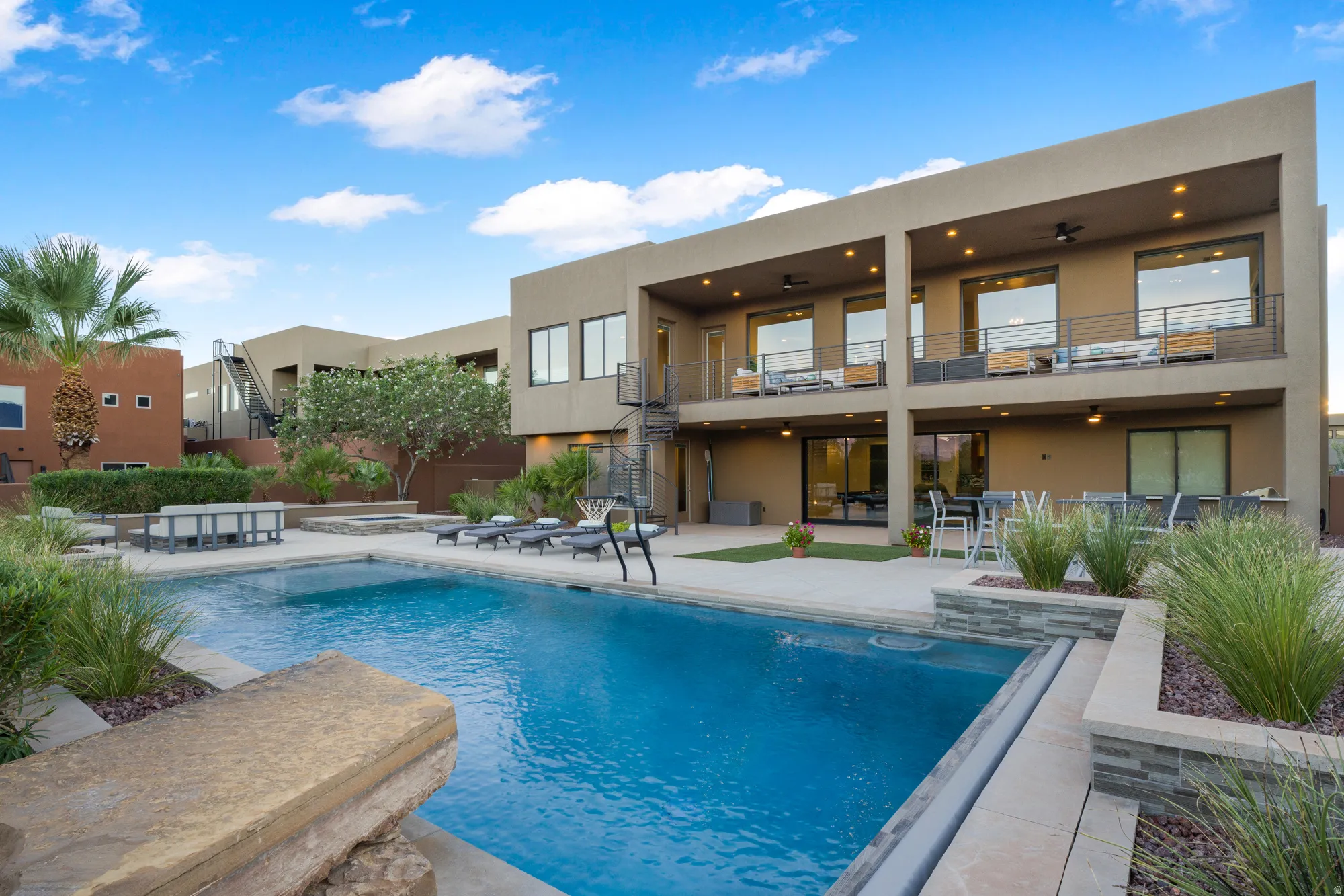 Expansive outdoor living area featuring a rectangular swimming pool, integrated spa, and desert-inspired landscaping