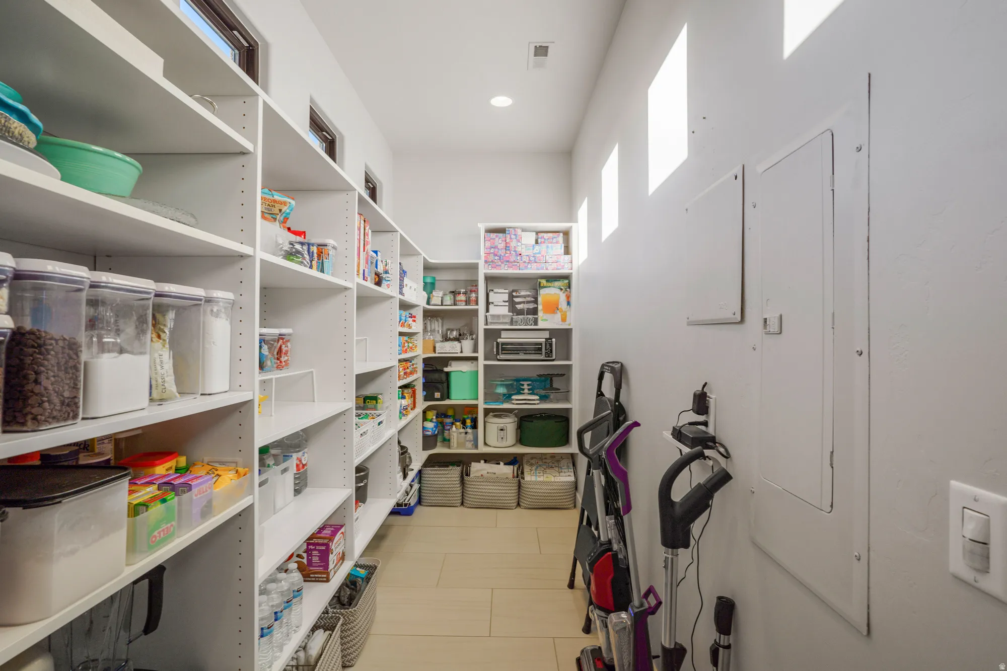 Extensive pantry with built-in shelving, wood-finish flooring, and natural light from transom windows
