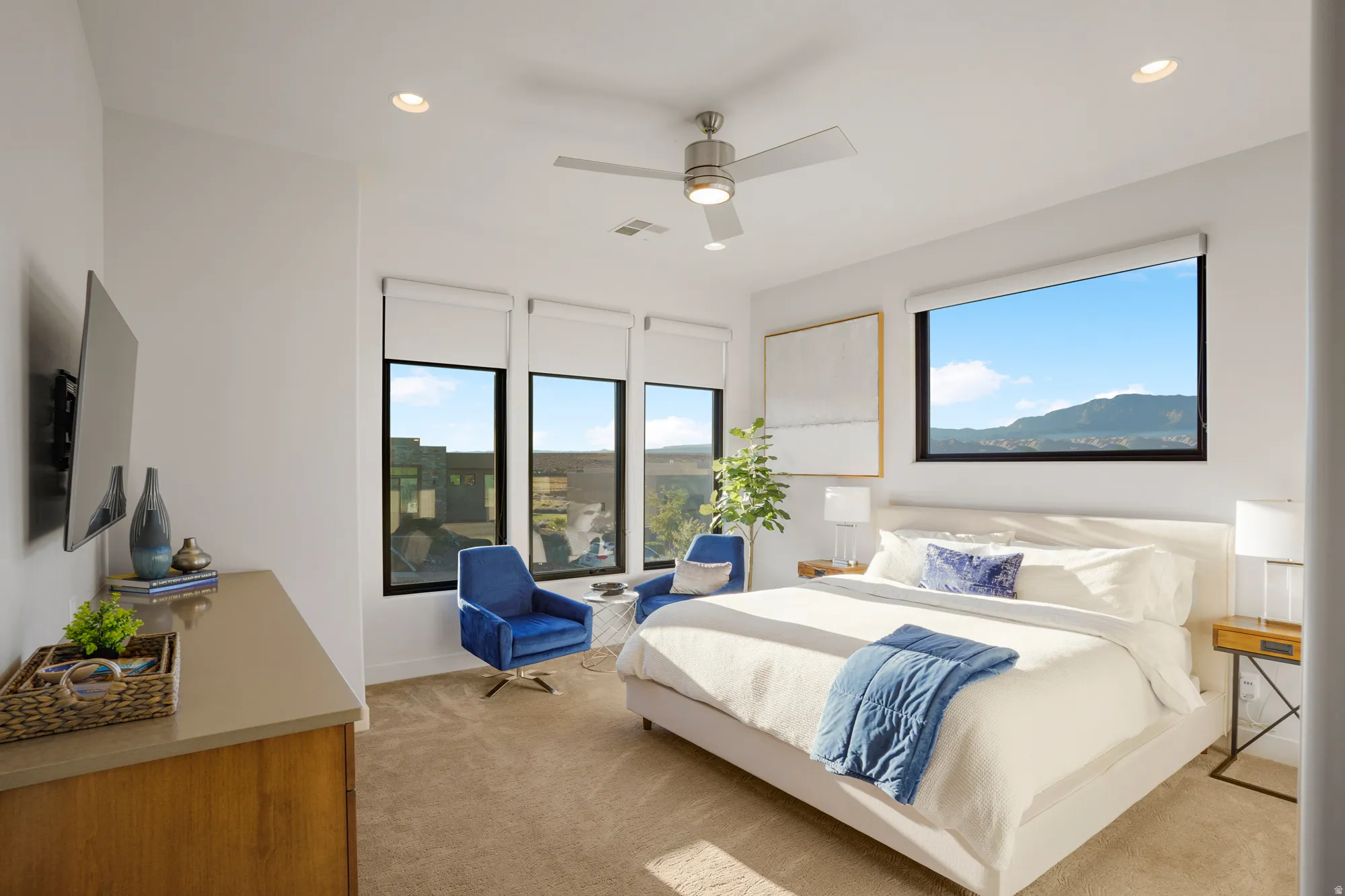 White walls with recessed lighting, large windows with roller shades, and a ceiling fan