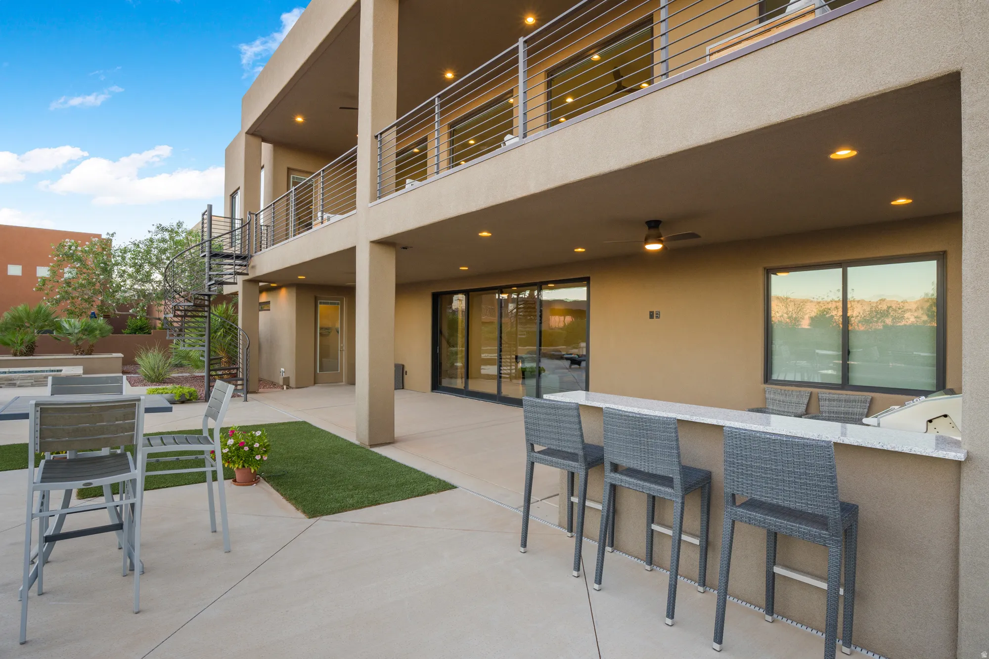 Multi-level stucco exterior with an outdoor kitchen, spiral staircase, and a covered patio area