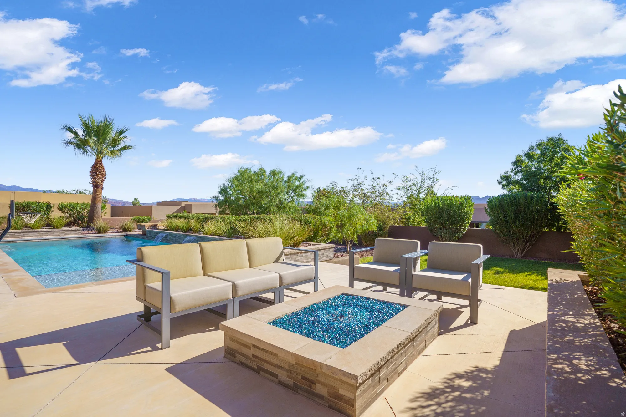 Paved patio with a built-in fire pit, swimming pool, and landscaping with mature trees