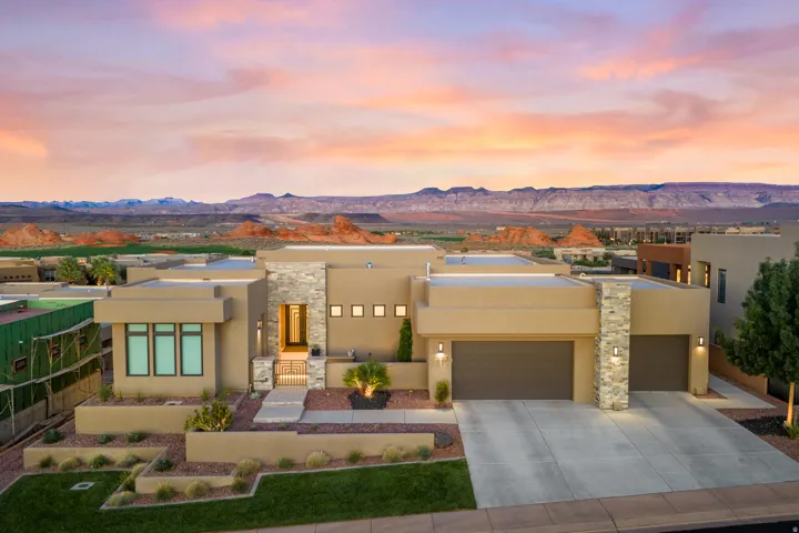 Contemporary exterior with a flat roofline, stone accents, multiple garage bays, and desert landscaping