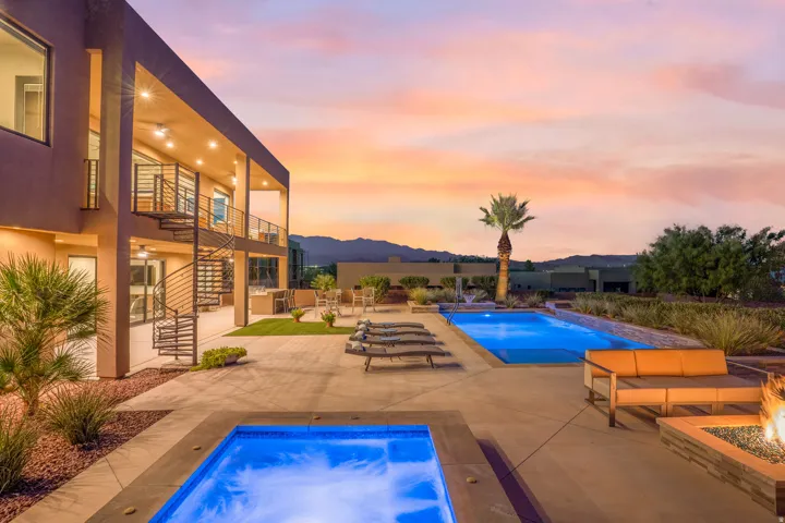 Expansive concrete patio featuring two pools, a spa, and a built-in fire pit