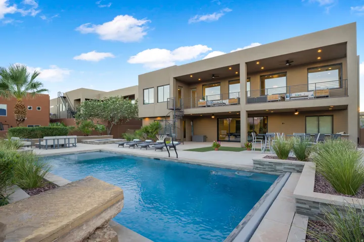 Expansive outdoor living area featuring a rectangular swimming pool, integrated spa, and desert-inspired landscaping