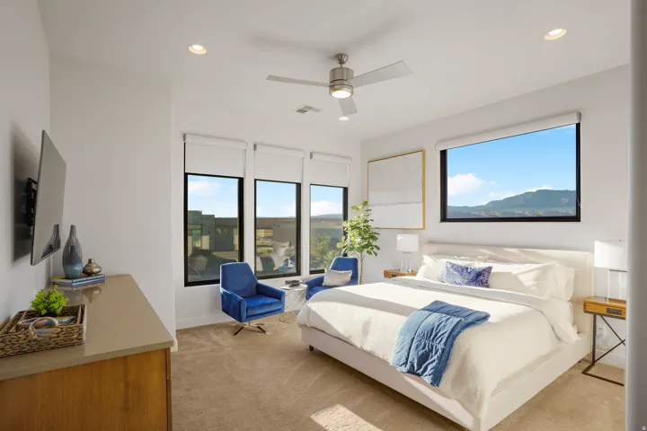 White walls with recessed lighting, large windows with roller shades, and a ceiling fan
